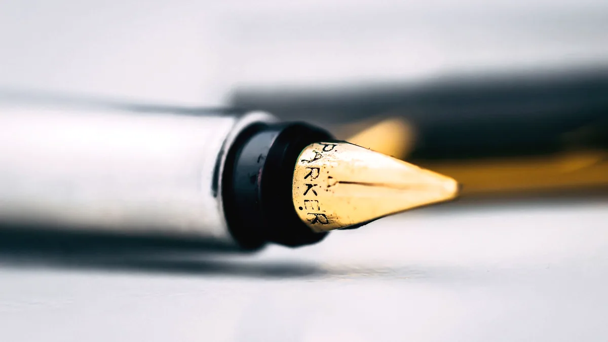 The nib of a pen, close enough to see the ink on it.