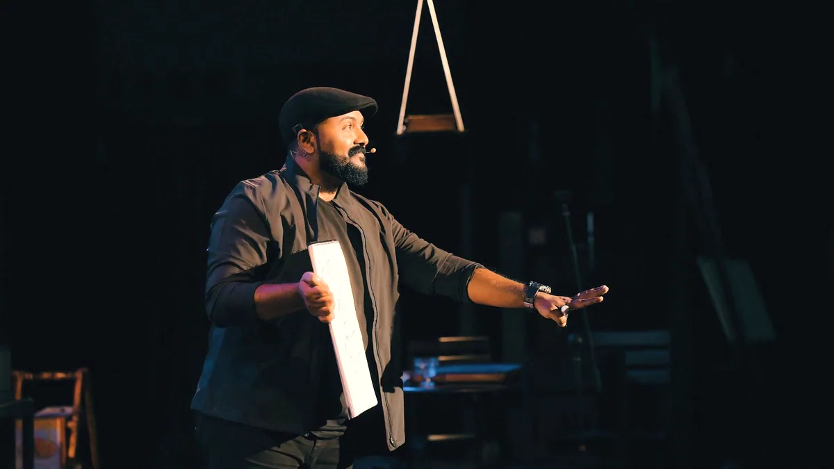 Someone on a stage, mid gesture, speaking into a microphone.