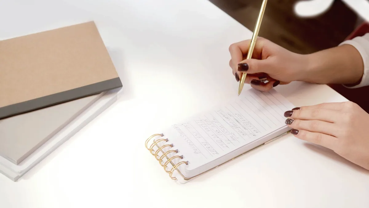 A hand writing in a notebook.