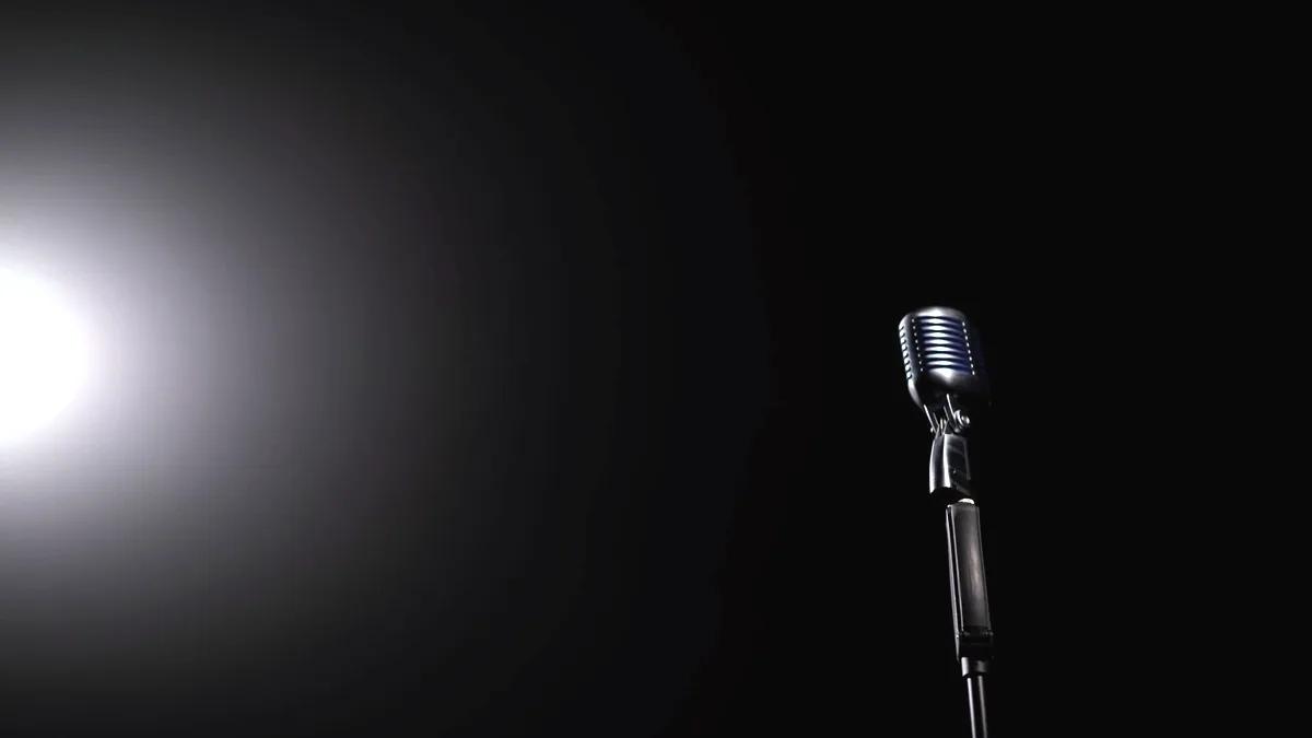 A microphone on a stand under a single stage light.