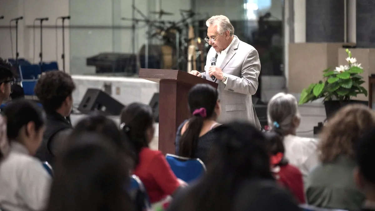 Someone holding a microphone and speaking to a room.