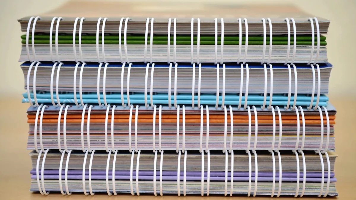 A stack of used notebooks on a desk.