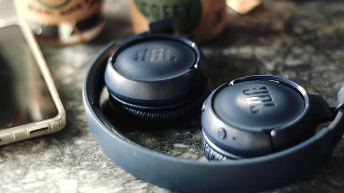 A pair of over ear headphones on a dark surface.