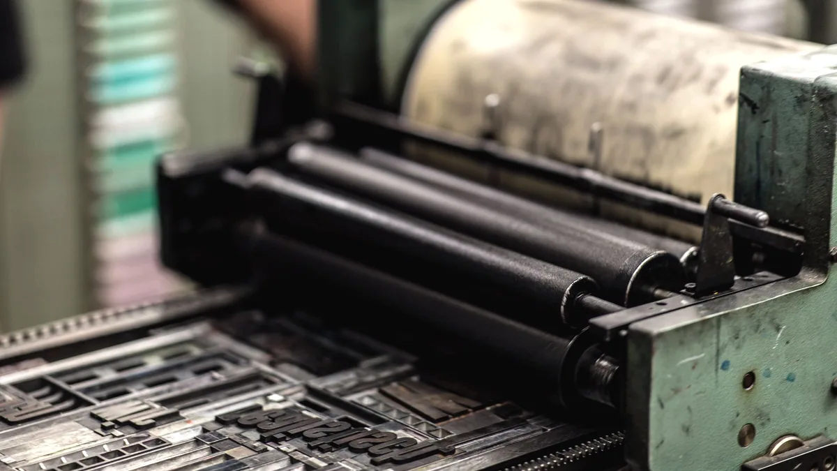 A press running sheets of paper in a print shop.