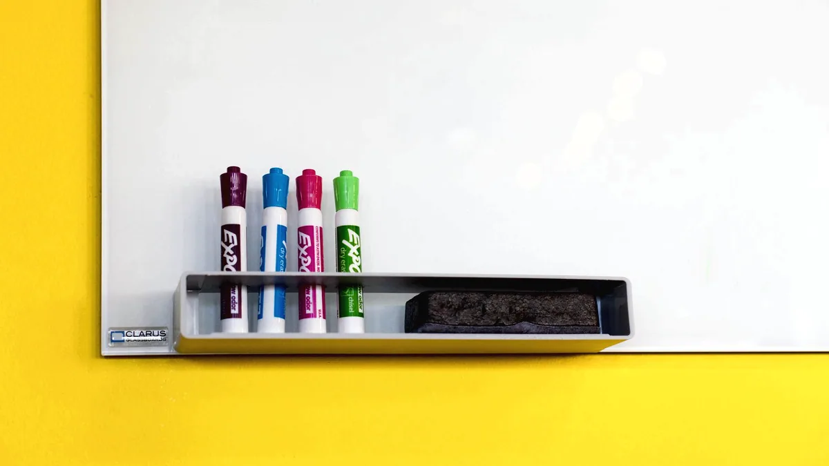 A whiteboard with markers on the ledge.
